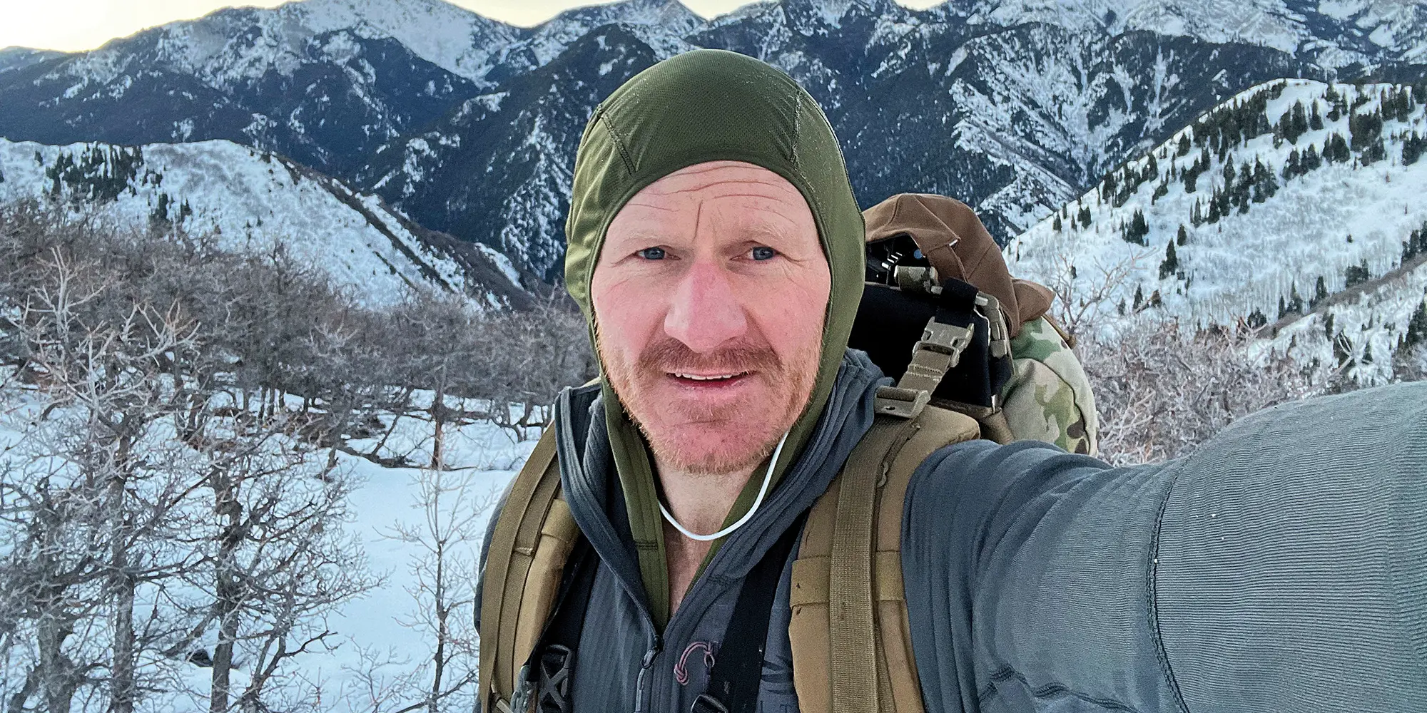 The author on a winter, weighted-pack-training hike through mountain terrain.  The author used the combination of hoods from his Sitka Core Lightweight Hoody and Sitka Heavyweight Hoody to constantly control the amount of heat leaving his body, and thereby maintain a consistent body temperature (minimize sweating) through varied-steepness terrain.