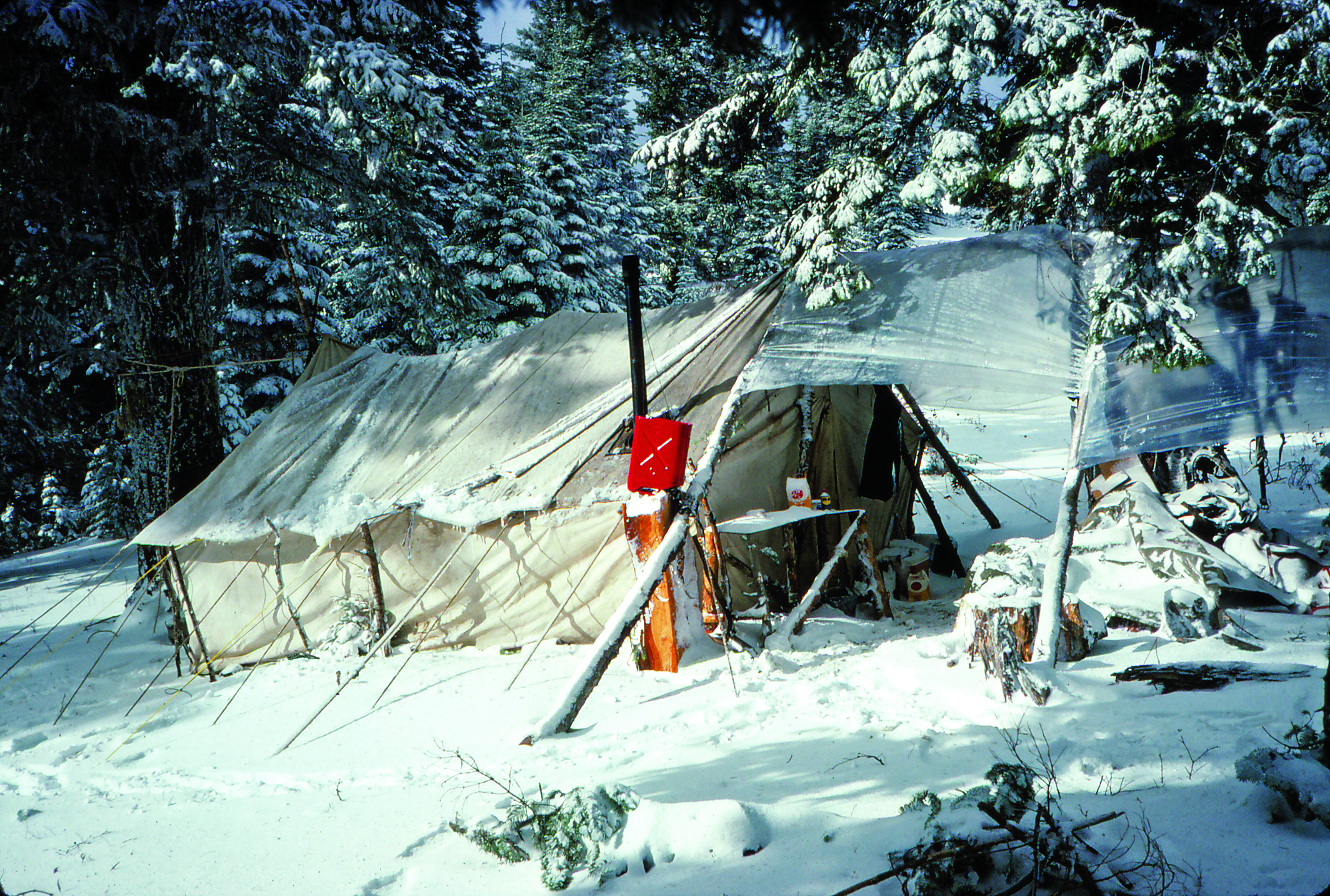 A canvas wall tent set up in the snow.