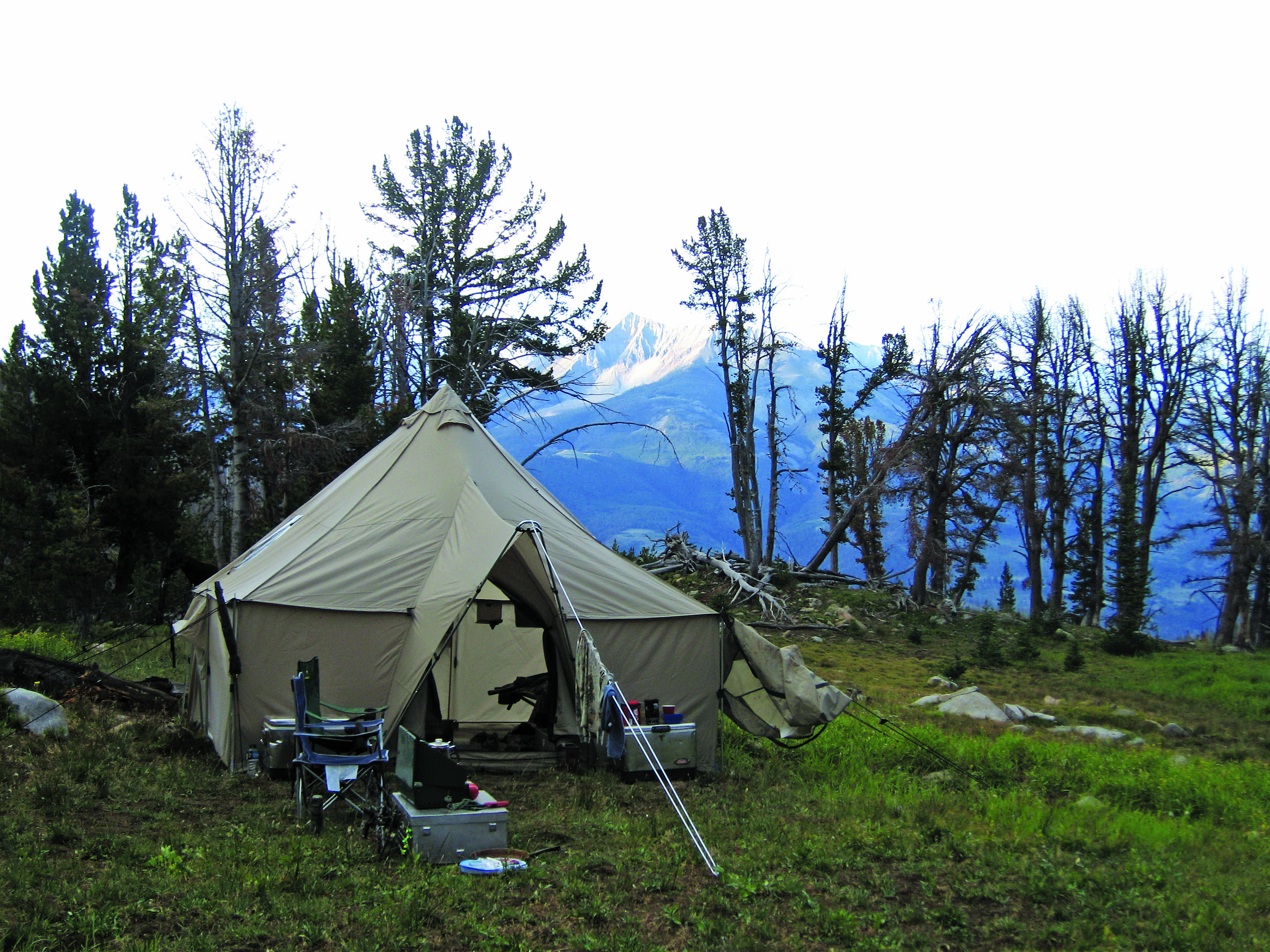 a canvas wall tent set up in the mountains.