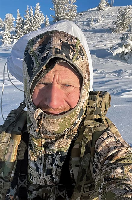The author post holing in deep snow on a December mountain archery hunt with temperatures below zero. The articulated hood, like that of the Sitka Heavyweight Hoody, is critical to keep your head and neck covered and to minimize heat loss from your head.